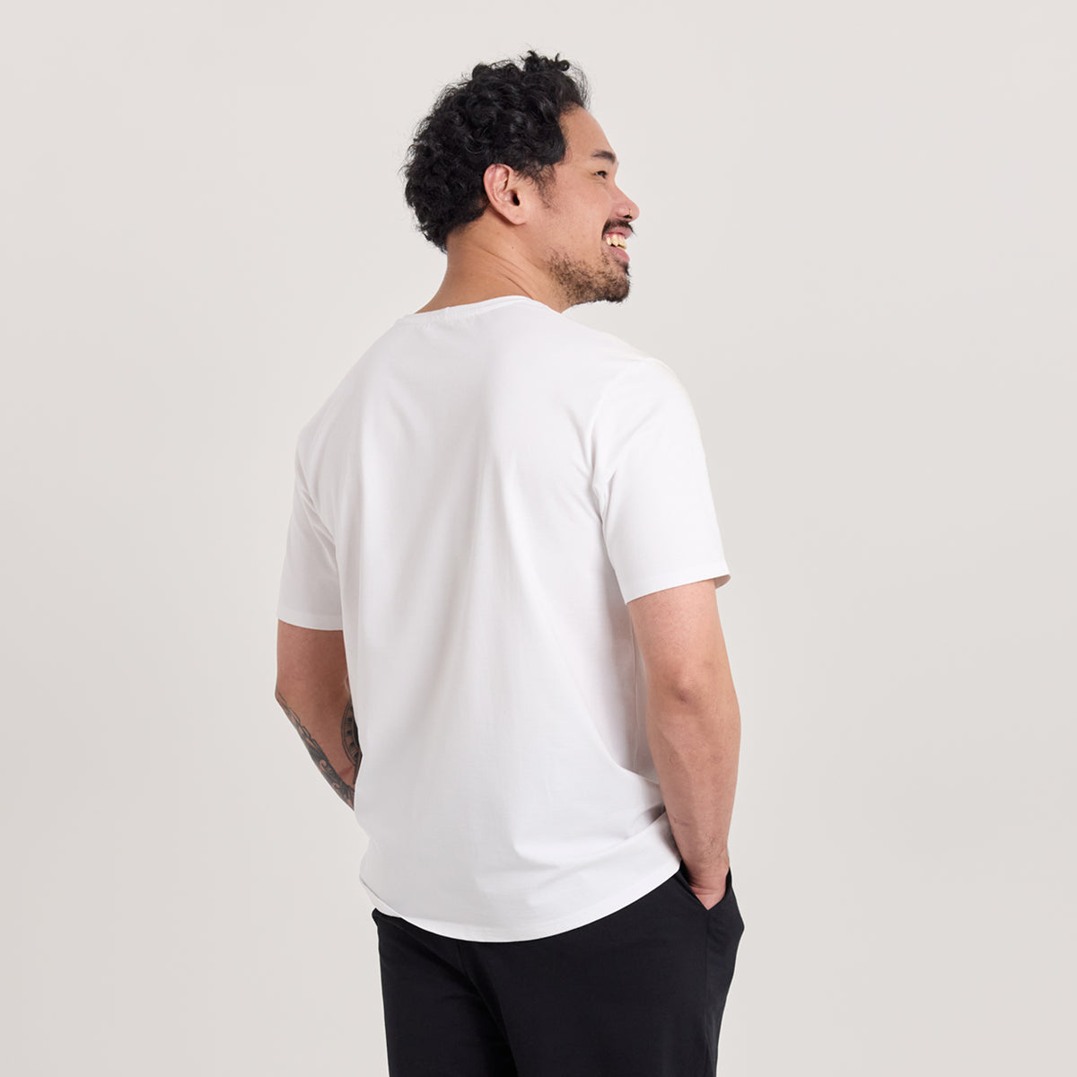 Mies takaapäin valkoisessa unisex-mallisessa t-paidassa, missä pyöreä pääntie