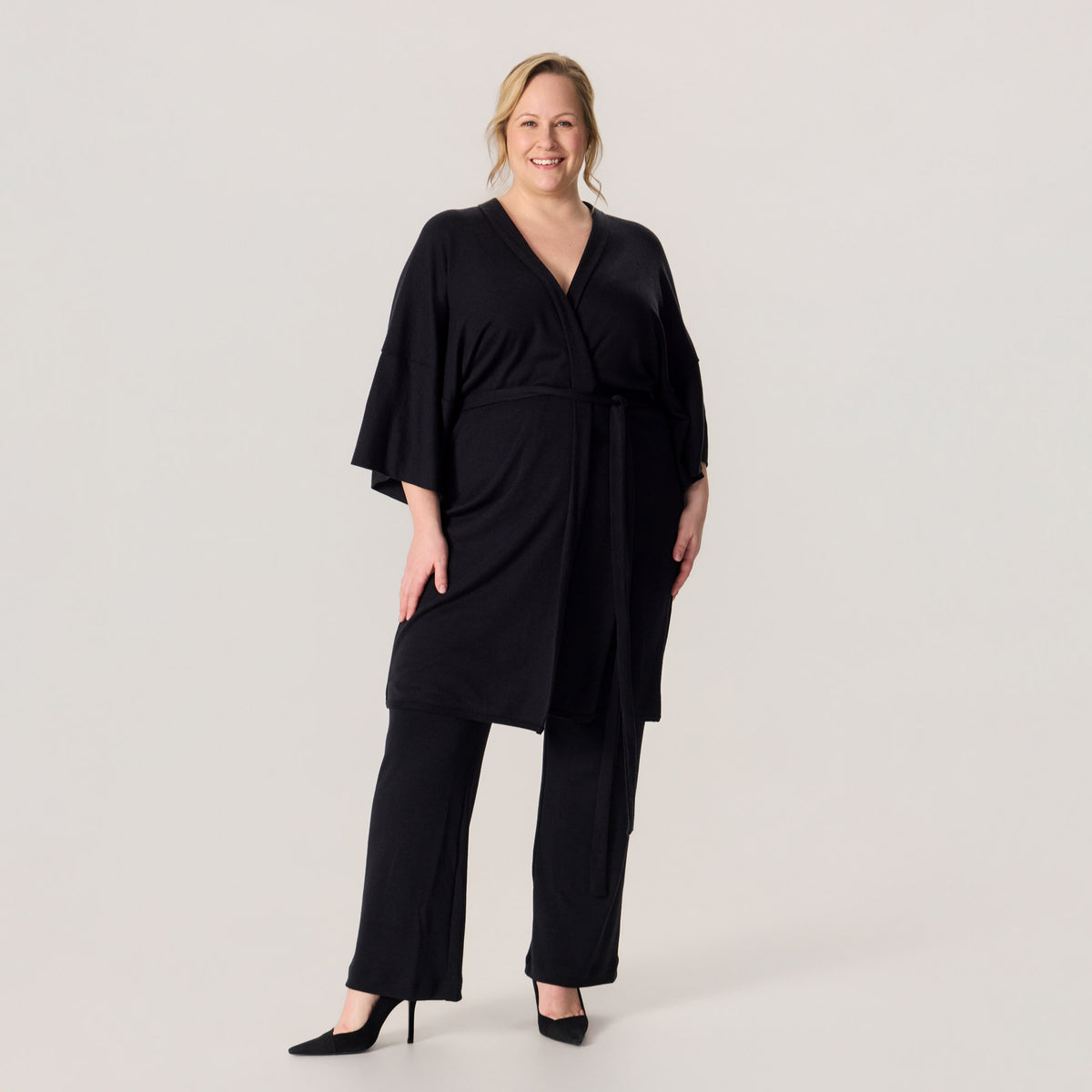 Merinosilkkinen HAIKU kimono ja merinovillaiset rennot neulehousut. Mallilla on korkokengät jalalassa, ja asukokonaisuus on näyttävä ja juhlallinen.